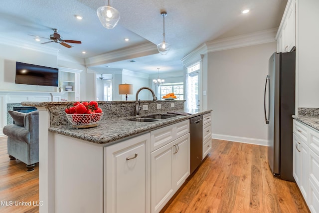 kitchen with sink, appliances with stainless steel finishes, pendant lighting, a kitchen island with sink, and white cabinets