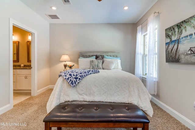 bedroom with light colored carpet and ensuite bath