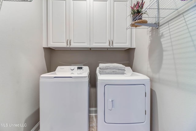 clothes washing area featuring washing machine and dryer and cabinets