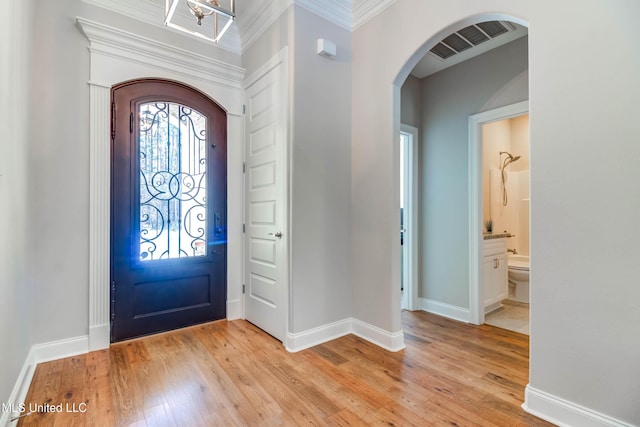 foyer entrance featuring ornamental molding, light wood-type flooring, and a wealth of natural light