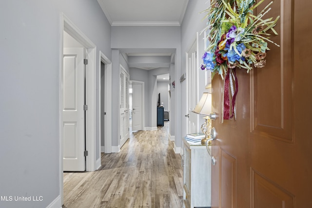 corridor with ornamental molding and light hardwood / wood-style flooring