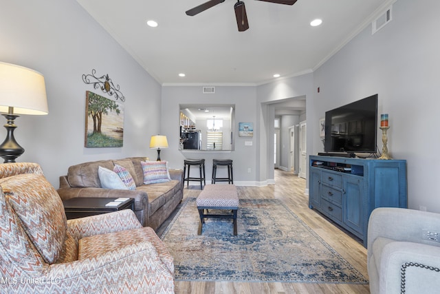 living room with light hardwood / wood-style flooring, ceiling fan, and crown molding