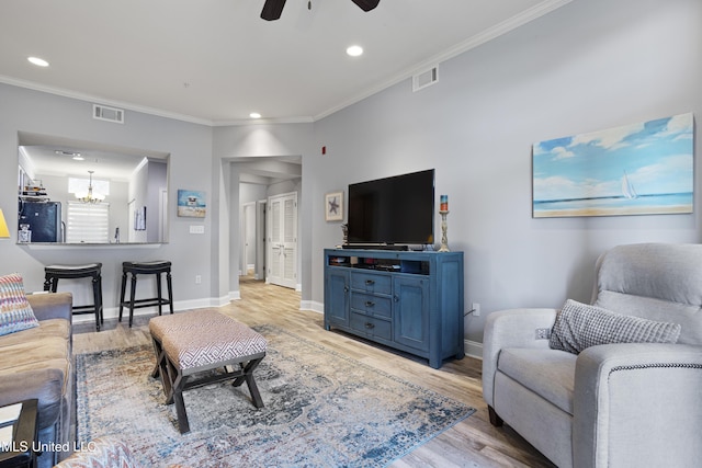 living room featuring ceiling fan with notable chandelier, light wood-type flooring, and crown molding