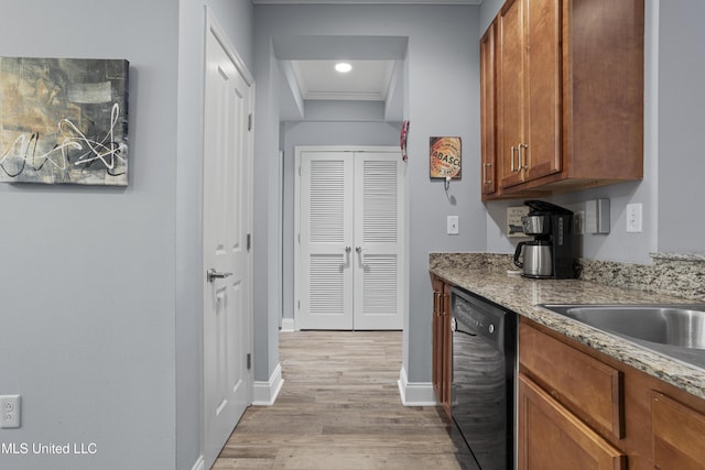 kitchen featuring crown molding, light stone counters, light wood-type flooring, and black dishwasher