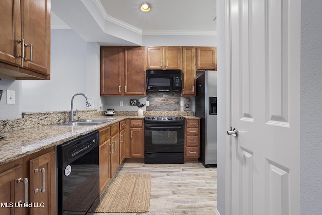 kitchen featuring sink, light stone counters, crown molding, black appliances, and light wood-type flooring