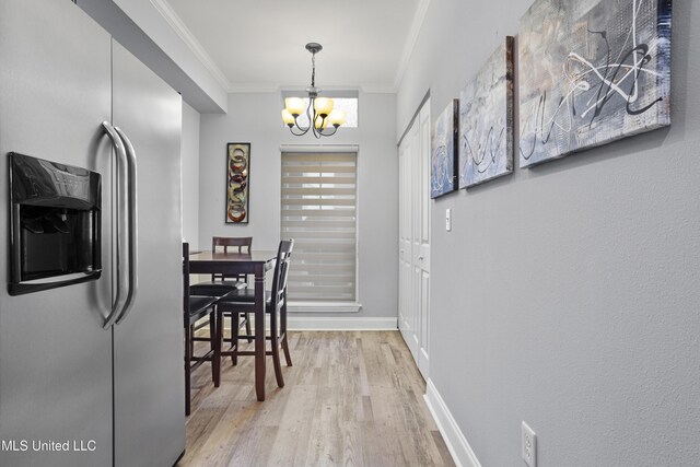 dining room with light wood-type flooring, crown molding, and a chandelier