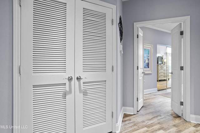 hallway with light hardwood / wood-style flooring and crown molding