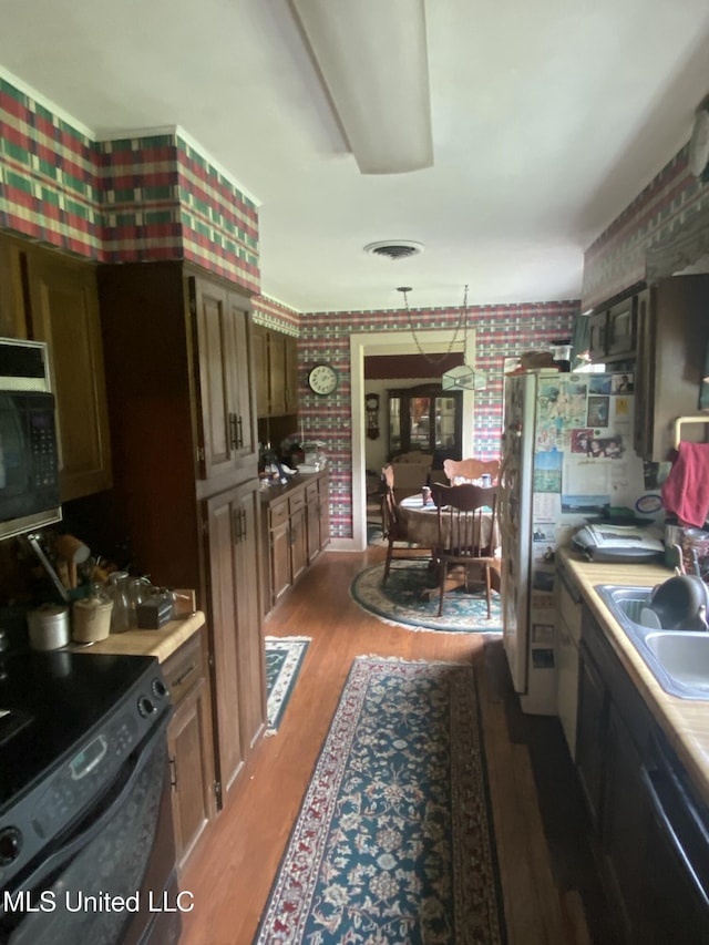 210 Colonial Cir, Jackson, MS 39211 - kitchen featuring wallpapered walls, black appliances, a sink, wood finished floors, and light countertops