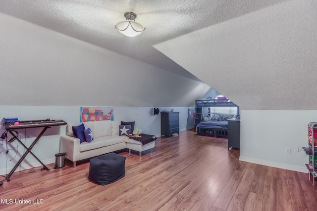 additional living space featuring wood finished floors, baseboards, and a textured ceiling