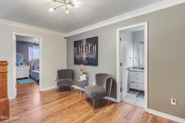 living area featuring a chandelier, light wood-style flooring, a textured ceiling, and crown molding