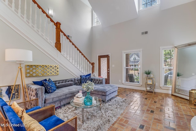 living room with brick floor, stairway, visible vents, and baseboards