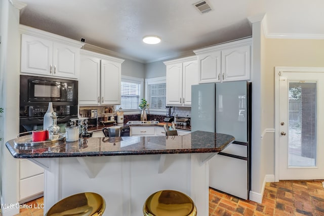 kitchen featuring visible vents, black appliances, and white cabinets