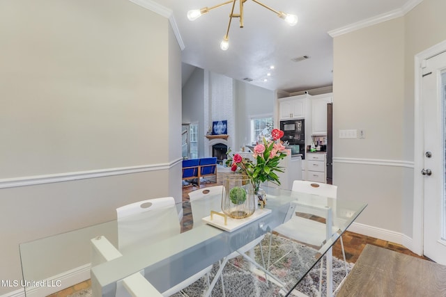 dining room with visible vents, vaulted ceiling, crown molding, a brick fireplace, and a notable chandelier