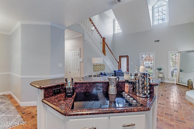 kitchen with visible vents, baseboards, open floor plan, brick floor, and black electric cooktop