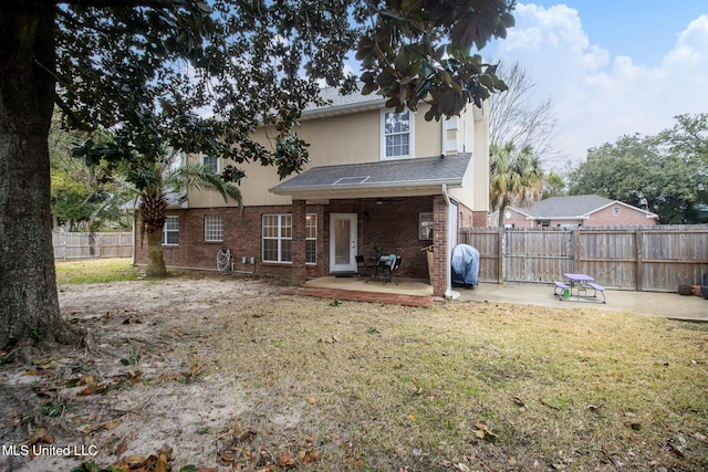 rear view of property featuring a patio, a yard, fence, and brick siding