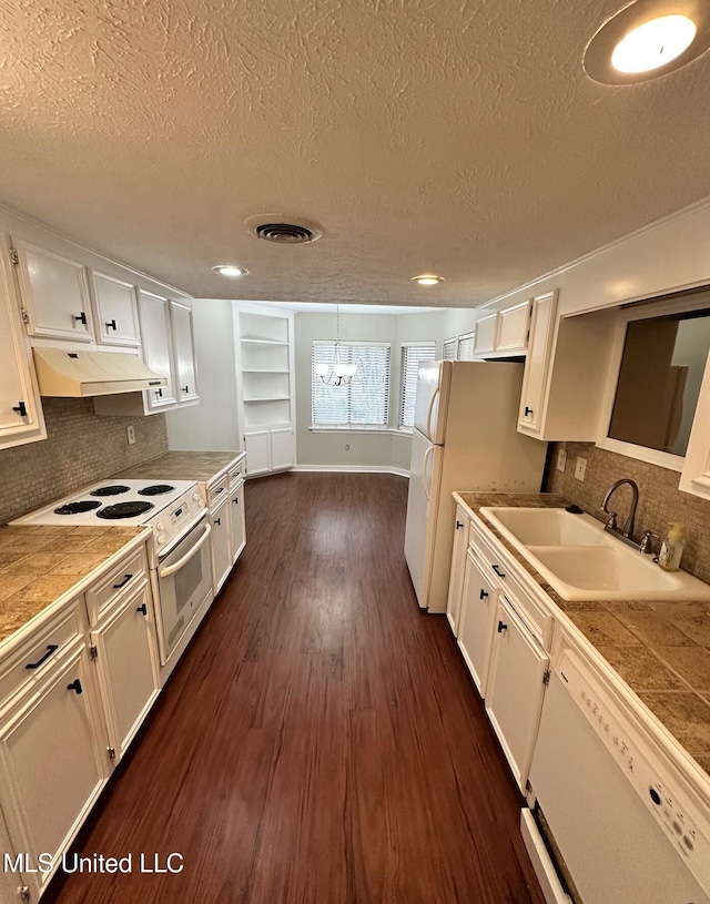 kitchen featuring white appliances, white cabinets, dark wood finished floors, under cabinet range hood, and a sink