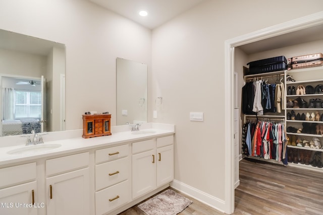 87139 Highpoint Dr, Diamondhead, MS 39525 - bathroom with double vanity, wood finished floors, recessed lighting, and a walk in closet