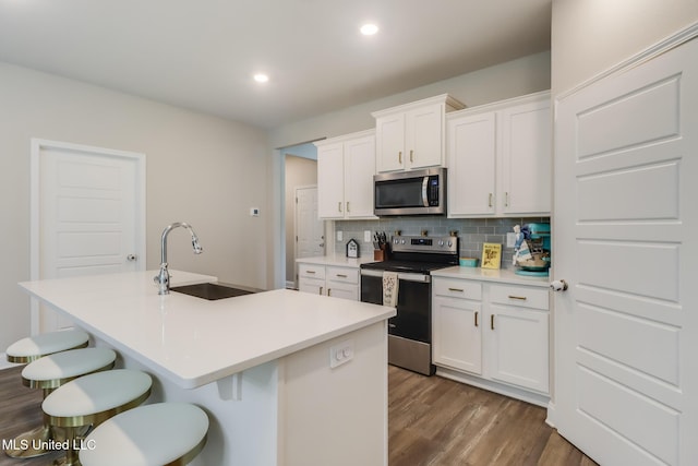 87139 Highpoint Dr, Diamondhead, MS 39525 - kitchen with stainless steel appliances, dark wood-type flooring, decorative backsplash, a kitchen bar, and an island with sink