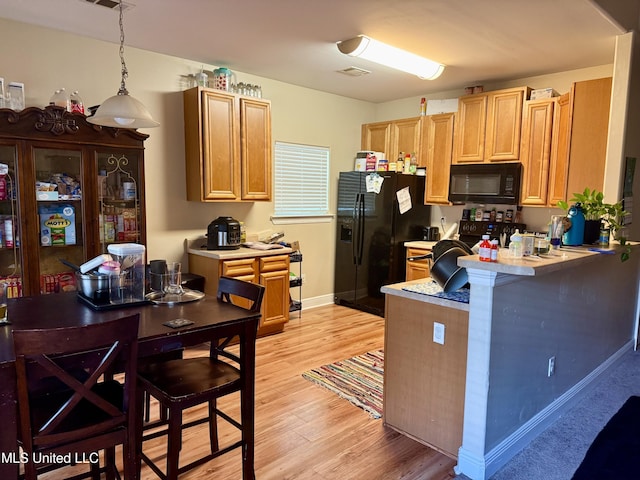6088 E Hinds St, Bay Saint Louis, MS 39520 - kitchen featuring black appliances, light countertops, light wood-style flooring, a peninsula, and hanging light fixtures