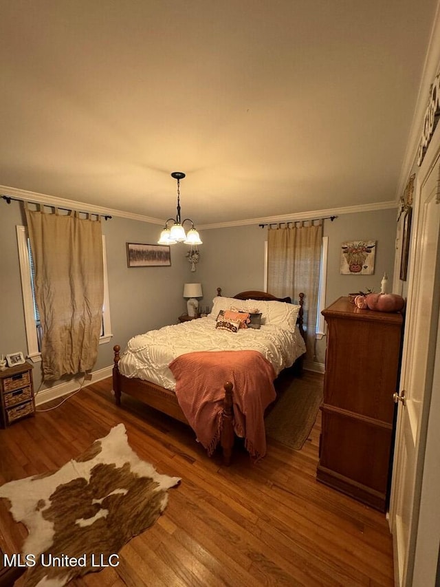 bedroom featuring hardwood / wood-style flooring, a notable chandelier, and crown molding