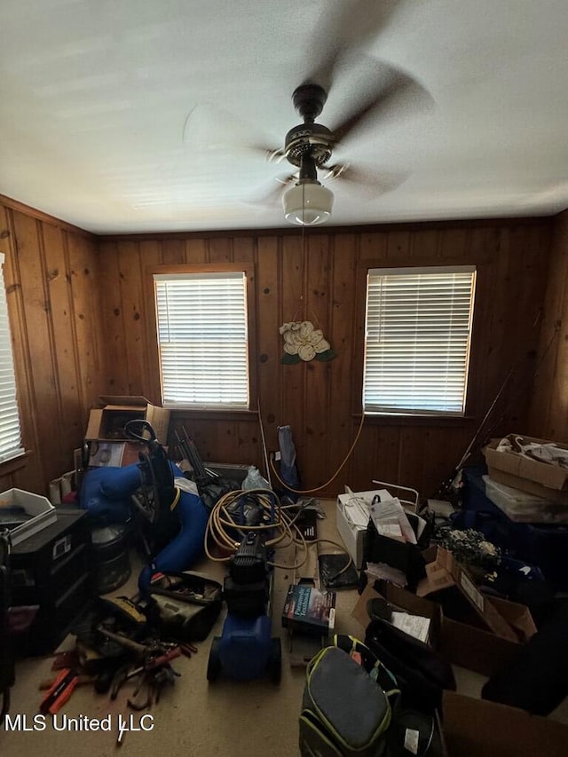 miscellaneous room featuring ceiling fan and wood walls