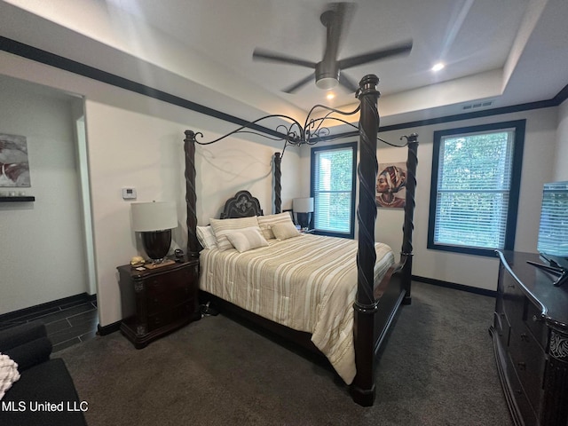 carpeted bedroom with a tray ceiling and ceiling fan