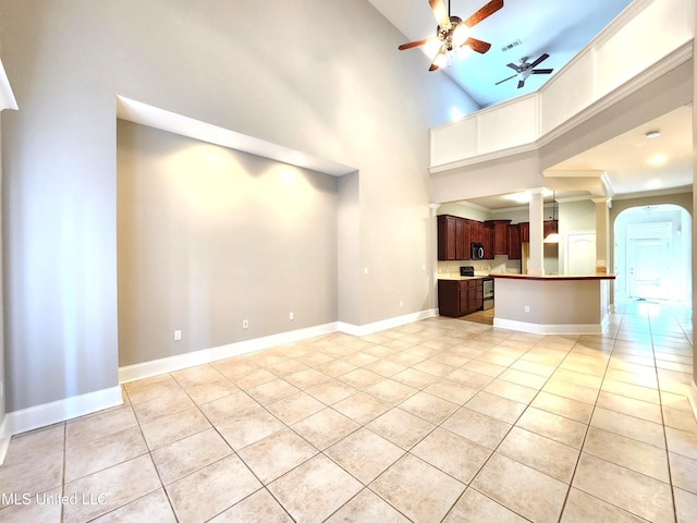 unfurnished living room featuring a high ceiling, light tile patterned flooring, and ceiling fan