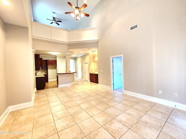 unfurnished living room with a high ceiling, light tile patterned flooring, and ceiling fan