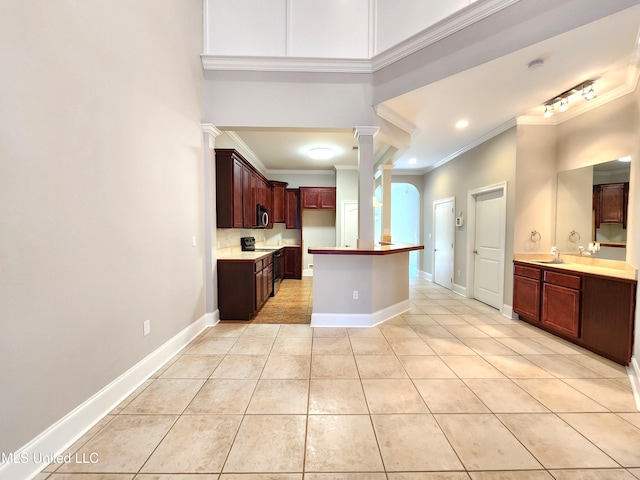 kitchen featuring stainless steel appliances, sink, decorative columns, ornamental molding, and light tile patterned floors