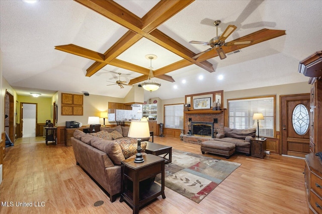 living room with ceiling fan, a fireplace, light hardwood / wood-style floors, and a textured ceiling