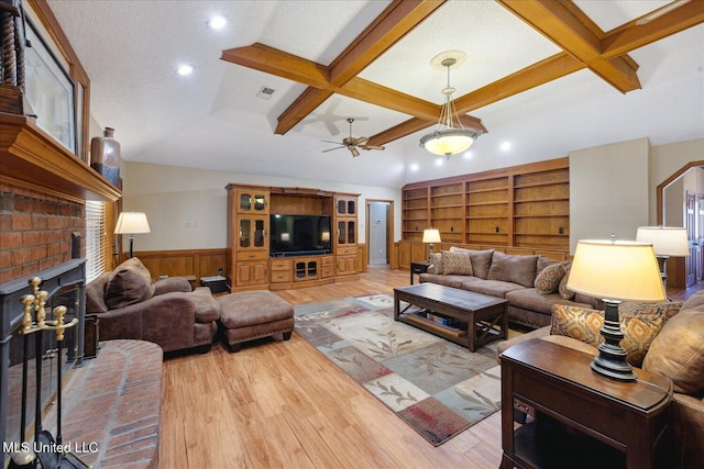 living room with beamed ceiling, light hardwood / wood-style floors, a brick fireplace, and coffered ceiling