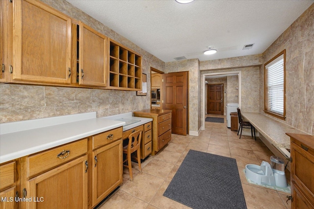 kitchen featuring oven, light tile patterned flooring, and a textured ceiling