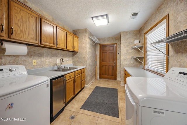 laundry room with cabinets, sink, washing machine and dryer, a textured ceiling, and light tile patterned flooring