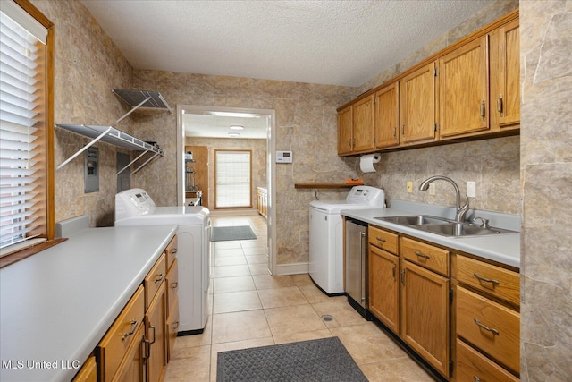 laundry area featuring washing machine and clothes dryer, sink, light tile patterned flooring, and cabinets