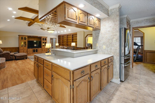 kitchen featuring ceiling fan, sink, beamed ceiling, kitchen peninsula, and stainless steel fridge