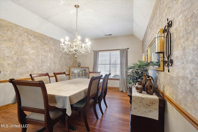 dining space featuring an inviting chandelier, wood-type flooring, and vaulted ceiling