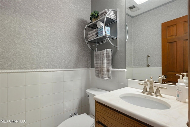 bathroom with vanity, toilet, and tile walls