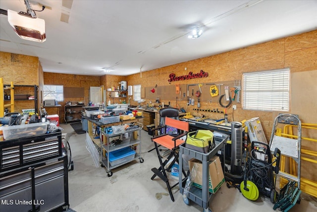 garage featuring a workshop area, wood walls, and a garage door opener