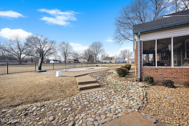 view of yard featuring a sunroom and ceiling fan