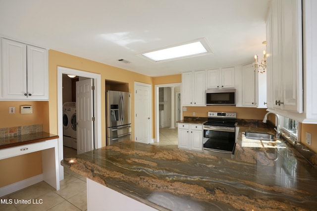 kitchen featuring sink, light tile patterned floors, appliances with stainless steel finishes, independent washer and dryer, and white cabinets