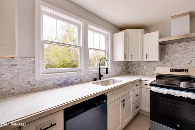 kitchen with sink, wall chimney exhaust hood, white cabinets, and appliances with stainless steel finishes