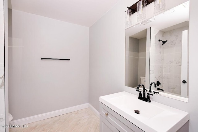 bathroom featuring hardwood / wood-style flooring, toilet, vanity, and a tile shower