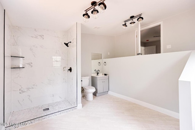 bathroom featuring vanity, toilet, and a tile shower