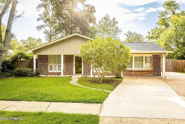 ranch-style house featuring brick siding, board and batten siding, a front yard, and fence