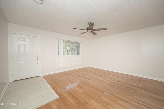 spare room featuring light wood-style flooring, baseboards, ceiling fan, and a textured ceiling