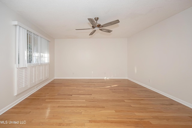 spare room with light wood-style floors, a textured ceiling, baseboards, and a ceiling fan