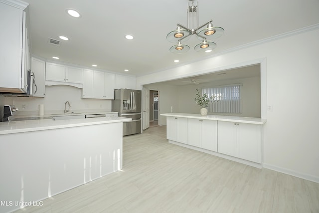 kitchen featuring visible vents, a peninsula, stainless steel appliances, light countertops, and a sink