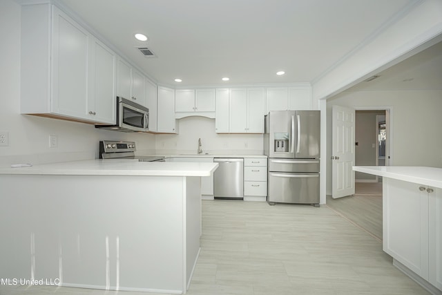 kitchen featuring stainless steel appliances, a peninsula, a sink, visible vents, and light countertops