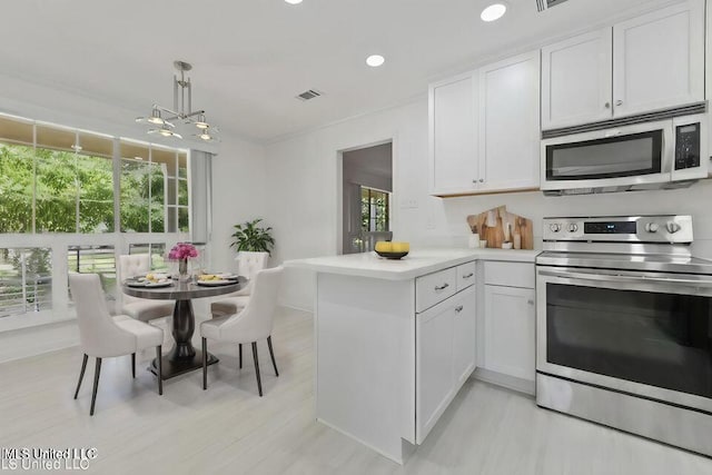 kitchen featuring a peninsula, visible vents, white cabinets, light countertops, and appliances with stainless steel finishes