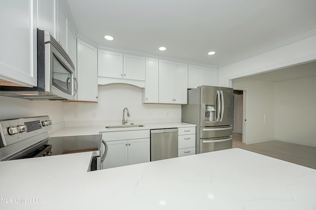 kitchen with appliances with stainless steel finishes, ornamental molding, white cabinetry, a sink, and recessed lighting